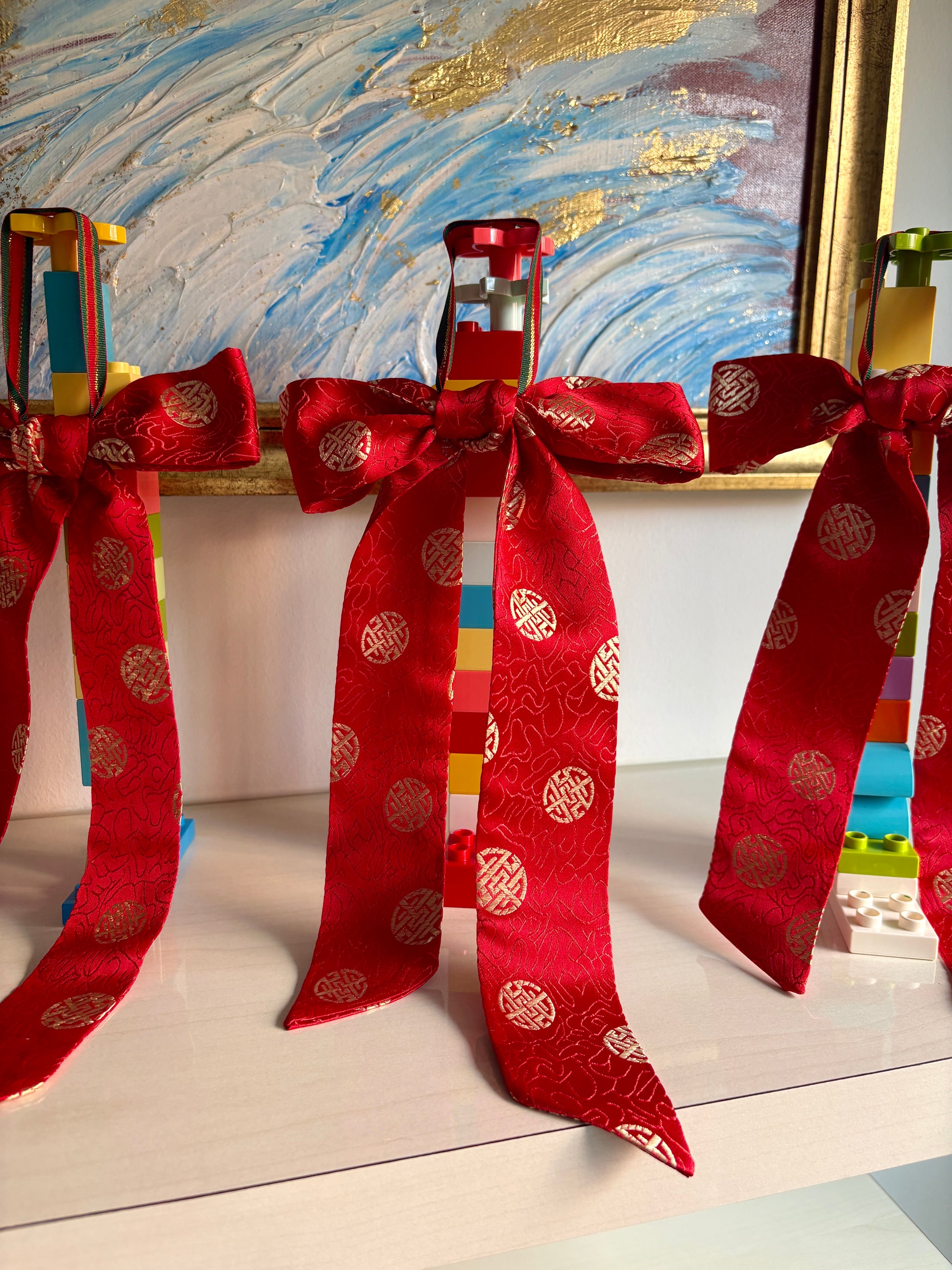 Red bows handmade in Singapore from red brocade fabric featuring Chinese characters.